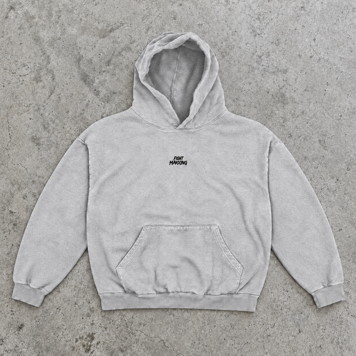 Fight Maxxing oversized hoodie in grey, laid flat on grey cement