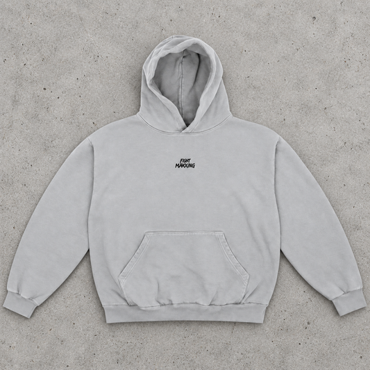 Fight Maxxing oversized hoodie in grey, laid flat on grey cement